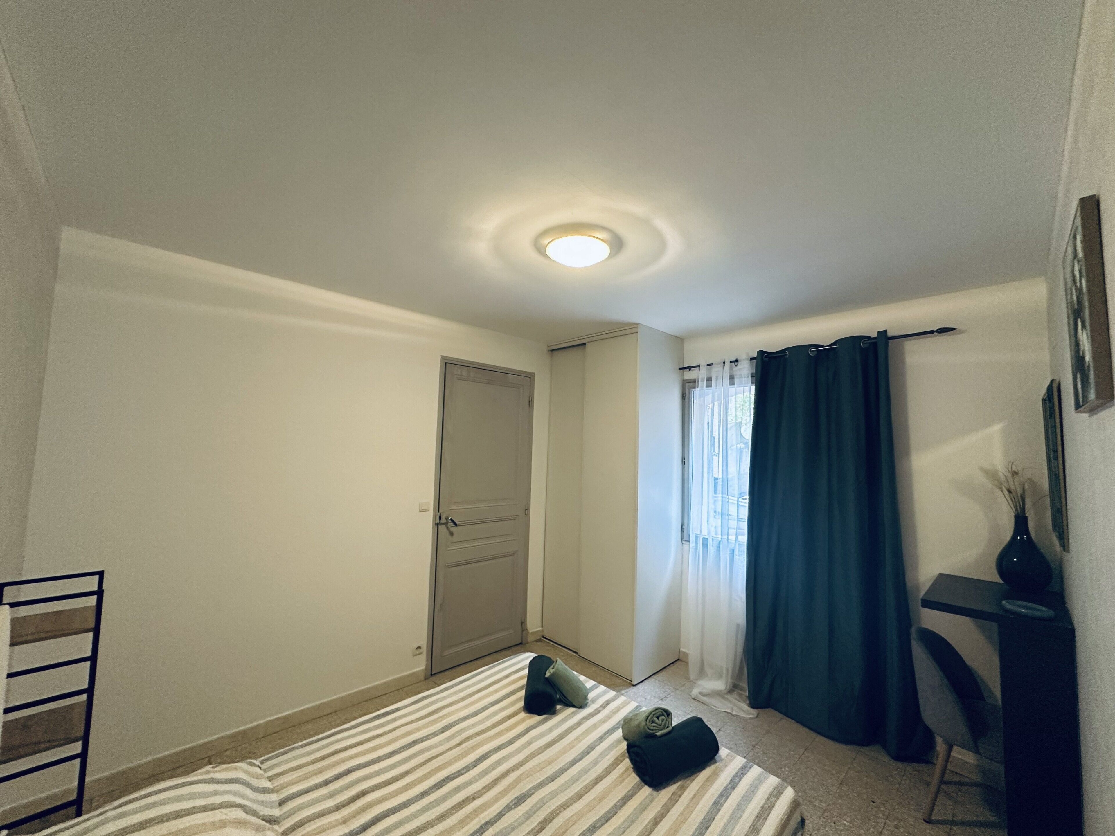 Une chambre d’hôtel avec un lit, un bureau, une chaise, une armoire et une porte de salle de bain.