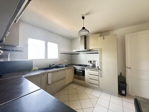Eine Küche mit Gasherd, Backofen, Spüle und einer Pendelleuchte.