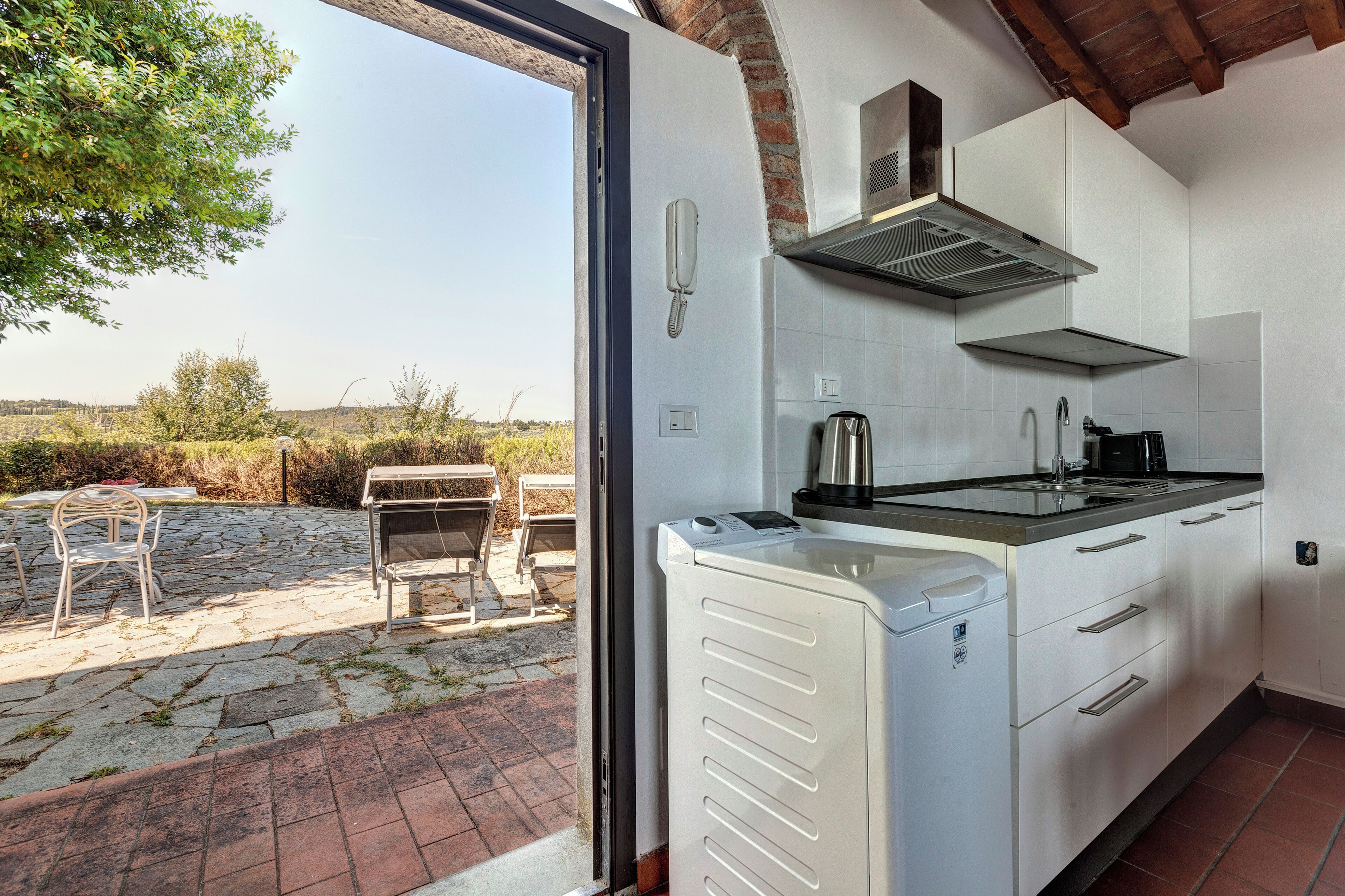 A kitchen with a built-in stove, a coffee maker, and a view of the outdoors.