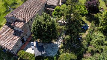 Un edificio de piedra con tejado de baldosas, rodeado de vegetación y un cielo despejado.