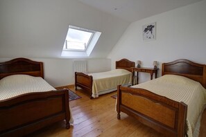 Une chambre à coucher avec deux lits en bois, un puits de lumière, un radiateur et une petite table avec des lampes.