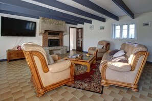 A living room with a fireplace, leather sofas, a coffee table, and a flat-screen TV. - Ty Frouden, 130 m² and 150 m from the sea (Plouescat)