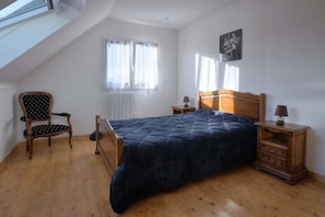 A bedroom with a bed, a chair, a nightstand, a window, and a radiator. - Ty Frouden, 130 m² and 150 m from the sea (Plouescat)