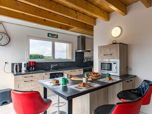 A modern kitchen with a wooden ceiling, a window with a view, and a dining area with red chairs. - Ty Frouden, 130 m² and 150 m from the sea (Plouescat)