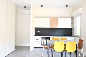 A modern kitchen with white cabinets, a black countertop, and a dining area with yellow chairs. - S372 – Sirolo, comfortable one-bedroom apartment with air conditioning and private parking (Sirolo)