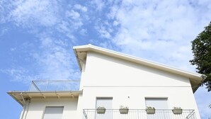Un edificio blanco con balcón, ventana y puerta.