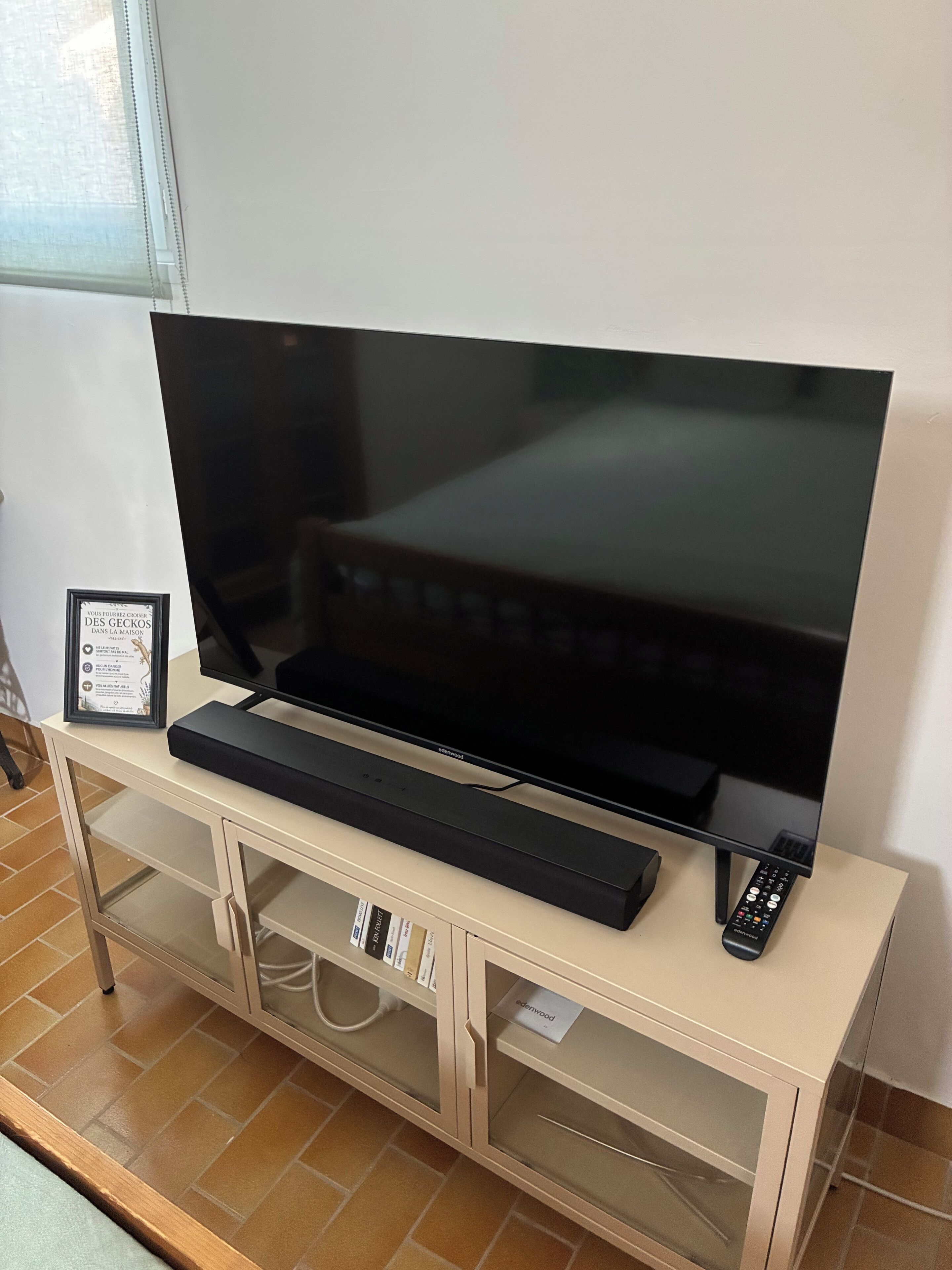 A flat-screen TV on a wooden TV stand with a remote control.
