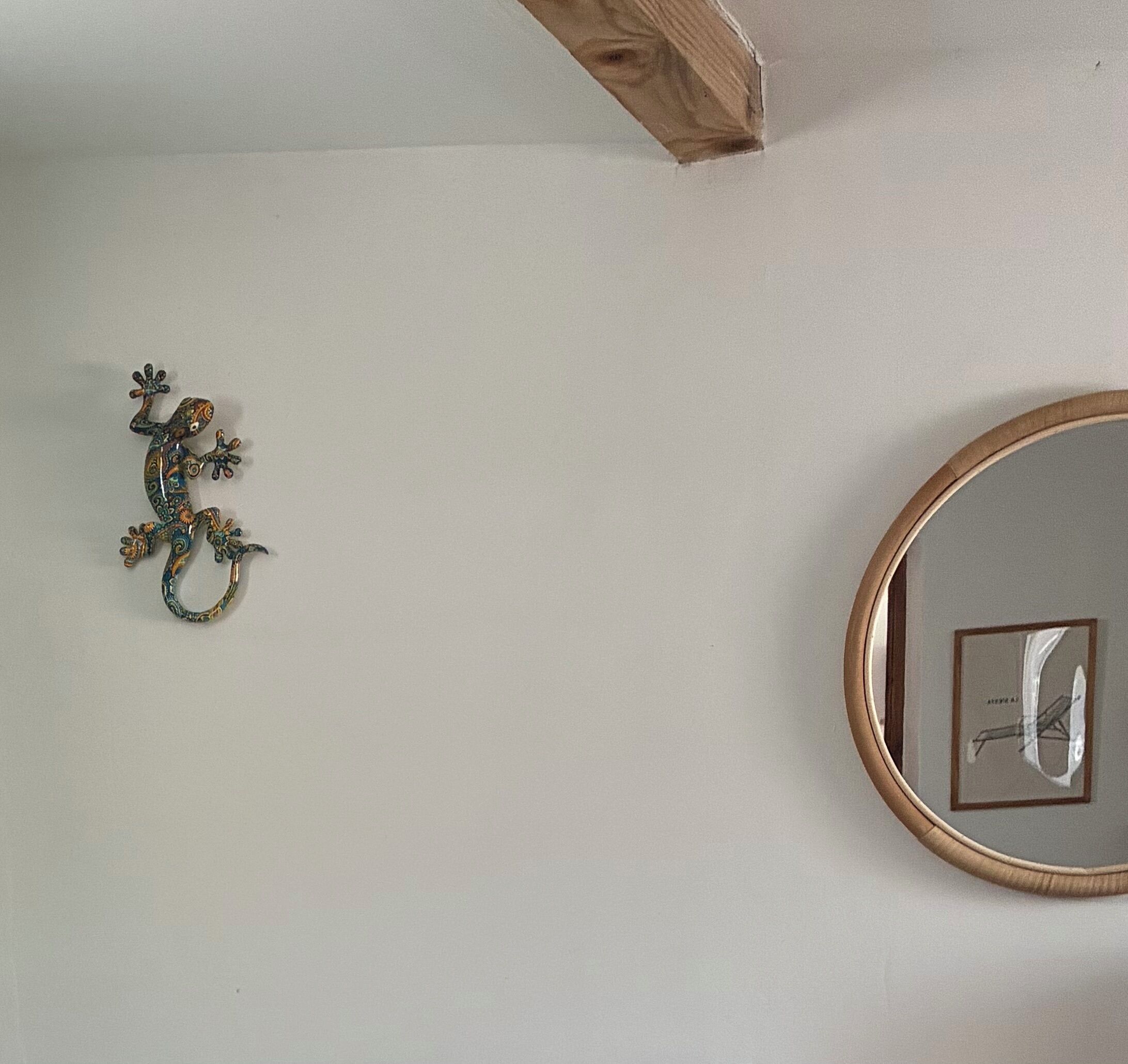 Un muro con un lucertola decorativa in metallo e un quadro incorniciato.
