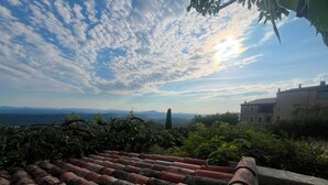 Un toit recouvert de tuiles en terre cuite, offrant une vue sur des montagnes lointaines et un ciel dégagé.