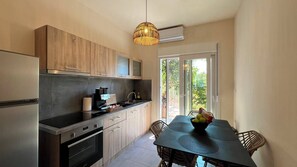 Une cuisine moderne avec un coin repas, un four encastré et une grande fenêtre qui laisse entrer la lumière naturelle.