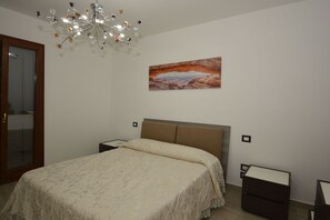 Ein Schlafzimmer mit einem Bett, einer Kandelaber, einem Gemälde und Nachttischen.