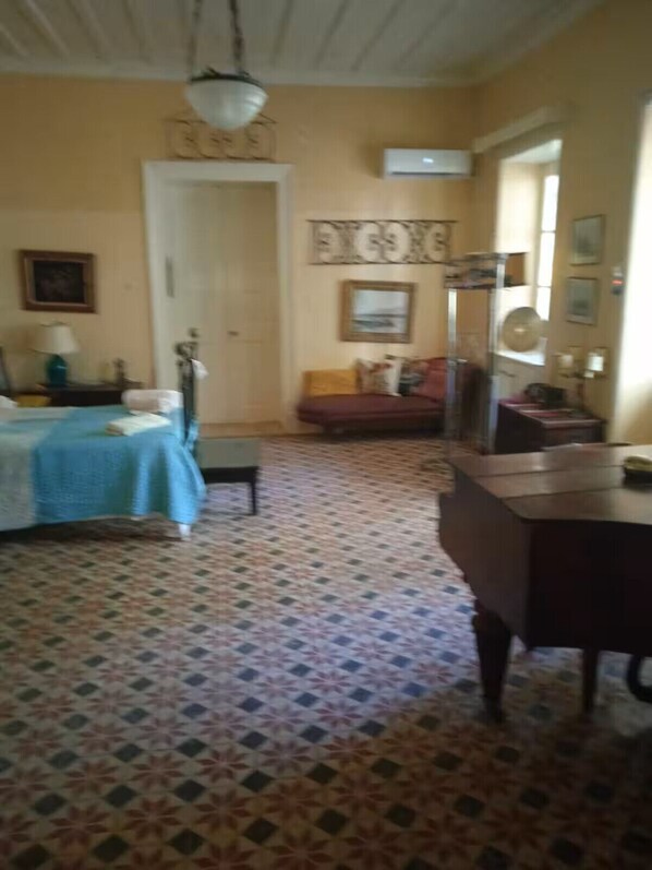 A room with a bed, a desk, a chair, a sofa, and a patterned floor.