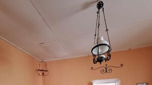 A bedroom with a bed, a desk, a chair, a suitcase, and a hanging light fixture. - Delightful 3-bedroom cottage with AC in Zakynthos (zakynthos)