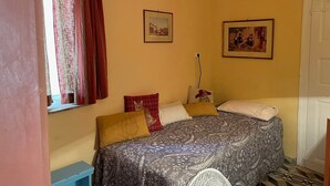 A bedroom with a bed, two pillows, a nightstand, a lamp, and two framed pictures on the wall. - Delightful 3-bedroom cottage with AC in Zakynthos (zakynthos)