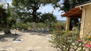 An outdoor patio area with a seating arrangement, a pergola, and a small garden with potted plants. - Delightful 3-bedroom cottage with AC in Zakynthos (zakynthos)