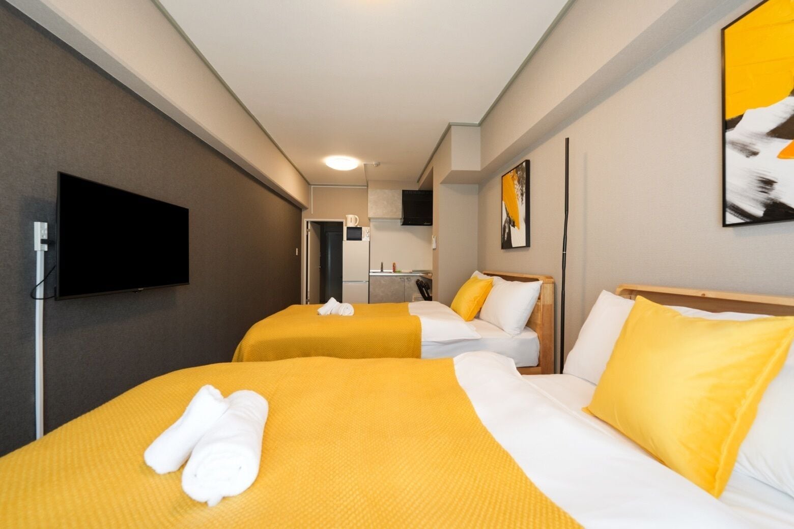 A hotel room with two beds, a television, and a kitchenette.