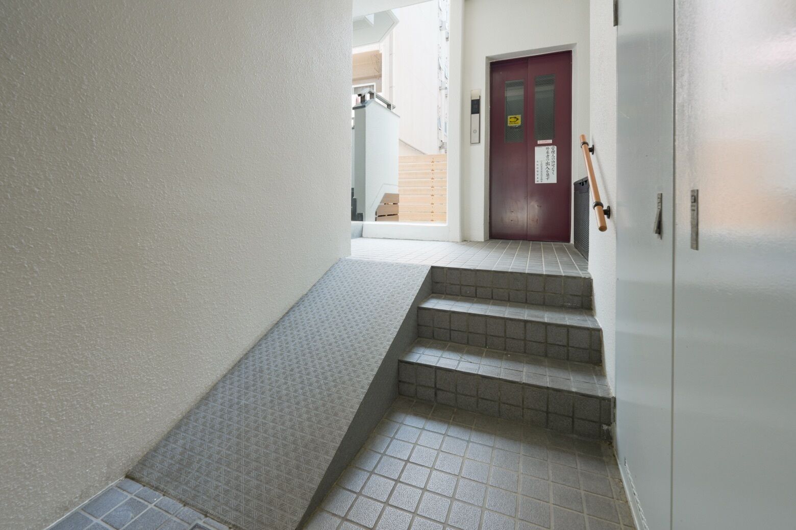A narrow hallway with a set of stairs leading to a door.