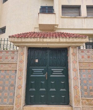 A building with a green double door, a tiled roof, and a patterned wall.