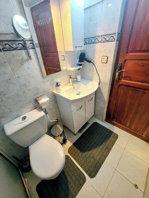 A bathroom with a toilet, sink, and mirror. - Vrbo Property (Fès)