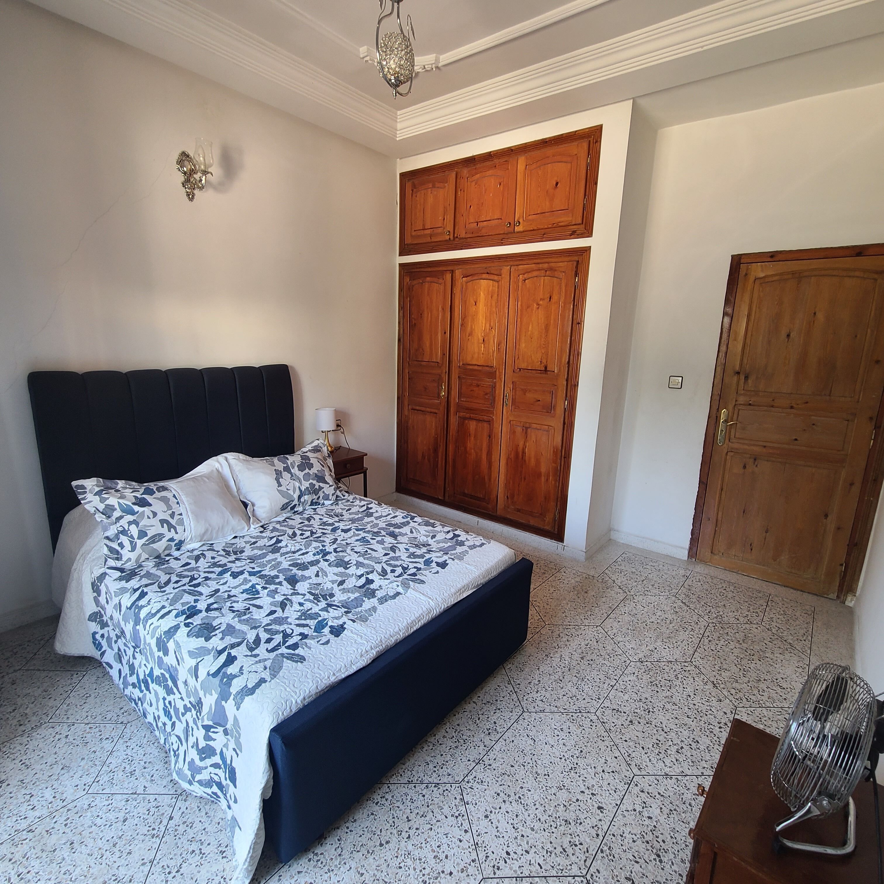 Une chambre à coucher avec un grand lit, une armoire en bois et une petite table de chevet.