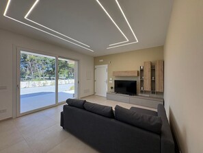 A modern living room with a sofa, TV, and built-in shelves.