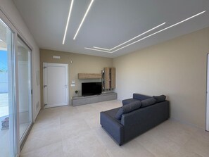A modern living room with a grey sofa, a flat-screen TV, and a wooden cabinet.
