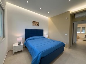 Ein modernes Schlafzimmer mit einem großen Bett, Nachttischen und einer Deckenleuchte.