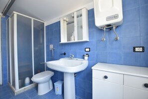 Ein Badezimmer mit Dusche, Toilette, Waschbecken und Schrank.