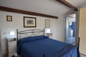 Ein Schlafzimmer mit Bett, Nachttischen, einem Bild im Rahmen und einem durchgegangenen Tür sichtbaren Badezimmer.