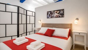 Habitación de hotel con cama, dos mesitas de noche, pared con diseño geométrico y un cuadro.