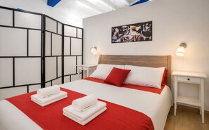 Ein Hotelzimmer mit einem Bett, zwei Nachttischen, einer Wand mit geometrischem Muster und einem Gemälde.