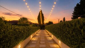 Un sendero bordeado por setos e iluminado con luces colgantes, que conduce a una estructura cónica.