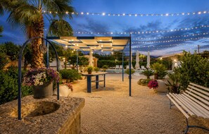 Ein Außenbereich mit Terrasse, einer Pergola, Sitzgelegenheiten und Lichterketten.