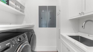 Une petite buanderie équipée d’un lave-linge à chargement frontal, d’un évier et de deux portes portant les inscriptions « C » et « D ».