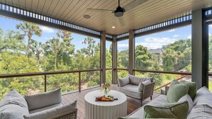 Un balcon spacieux offrant une vue sur une végétation luxuriante et un coin salon extérieur moderne.