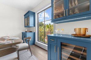 Una cocina moderna con armarios azules, una mesa de comedor con sillas y un ventanal con vistas a la vegetación.
