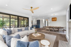 Una sala de estar moderna con un sofá grande, un comedor y una cocina al fondo.