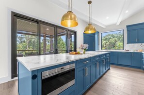 Una cocina moderna con armarios azules, encimera de mármol y horno empotrado.