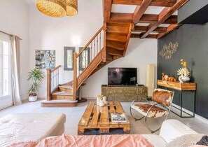 Ein modernes Wohnzimmer mit einer Holztreppe, einem Flachbildfernseher und einem Couchtisch.