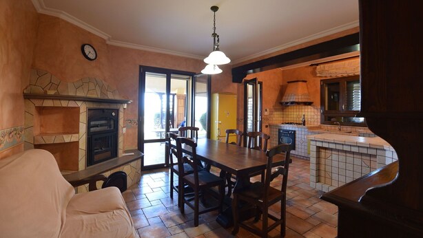 Un comedor con una mesa y sillas, una chimenea y una zona de cocina con estufa y fregadero.