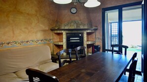 Un comedor con chimenea de piedra, una mesa de madera y un sofá.