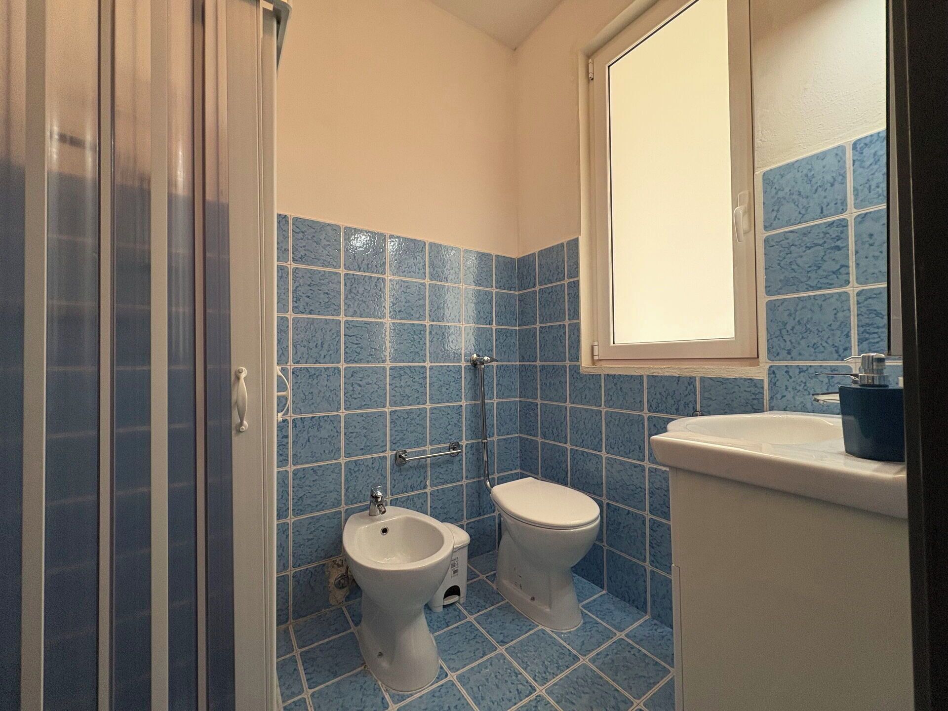 Une salle de bain équipée d’un bidet, de toilettes et d’une fenêtre.
