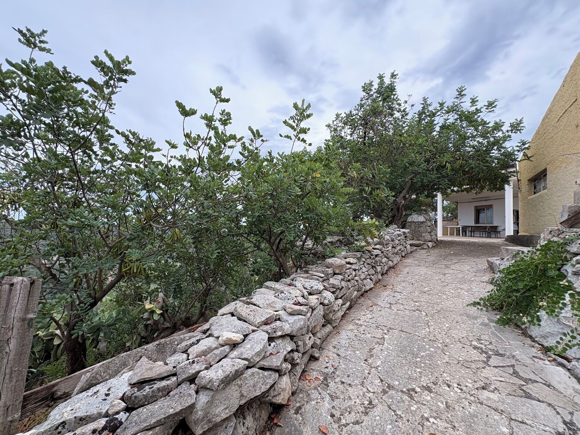 A stone pathway leading to a building with a covered outdoor seating area.