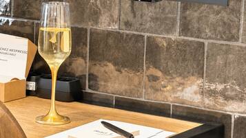 Una mesa con una copa de vino, un libro y un bolígrafo, frente a una pared de piedra con un televisor de pantalla plana montado arriba.