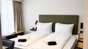 A double bed with a green headboard, a desk with a chair, and a window with curtains. - THE 8 HOTEL BUDAPEST (Budapest)