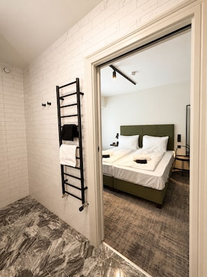 Una habitación de hotel con cama, baño con toallero y piso de mármol.