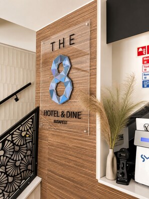 Una recepción con panel de madera y un letrero que indica 'The 8 Hotel & Dine Budapest'.
