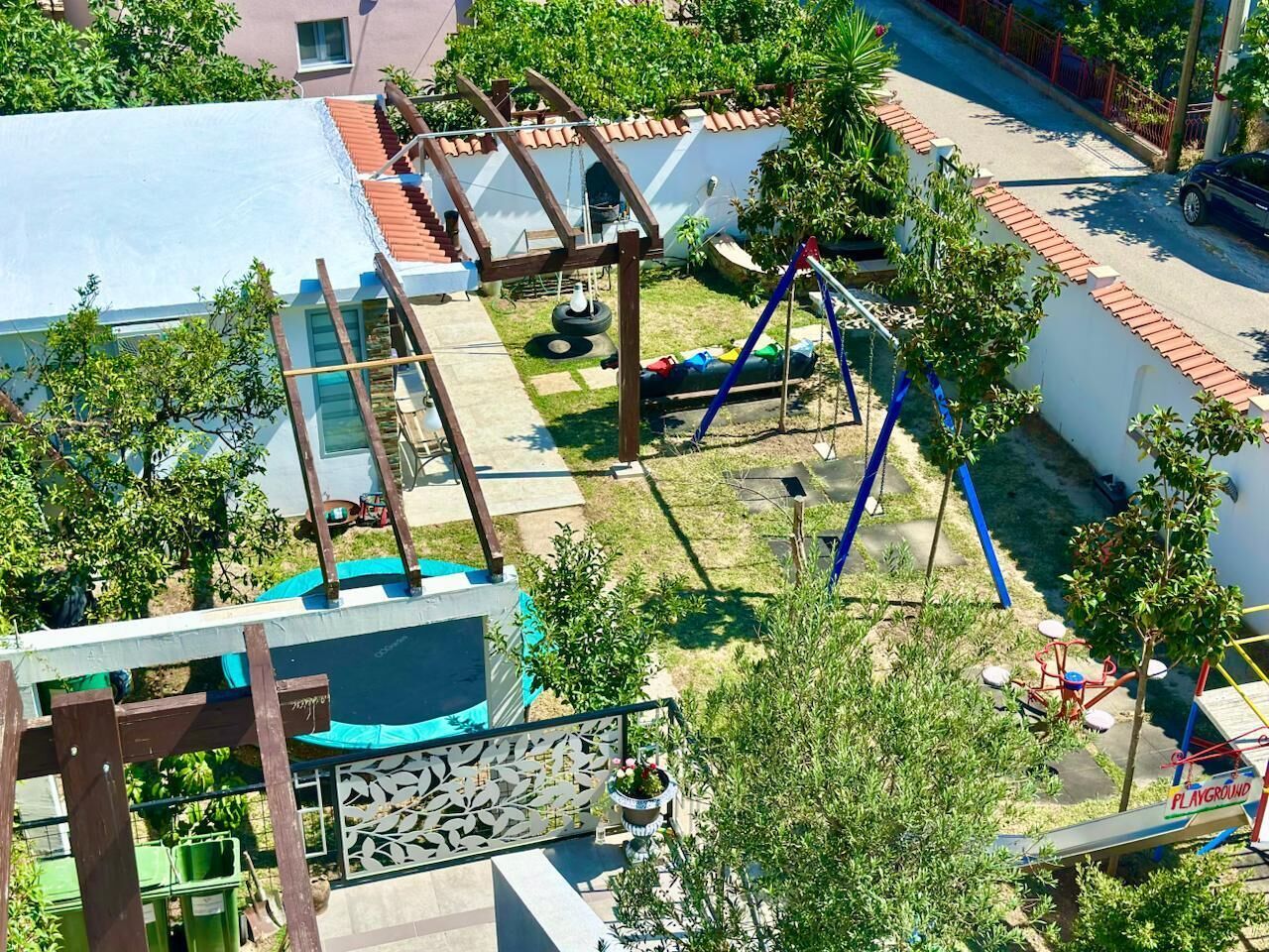 Un'area giochi con diverse strutture ricreative, una zona relax coperta e un piccolo giardino con piante in vaso.