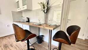 Una cocina moderna con encimera de madera, cuatro taburetes de bar, un lavamanos y un florero con flores.
