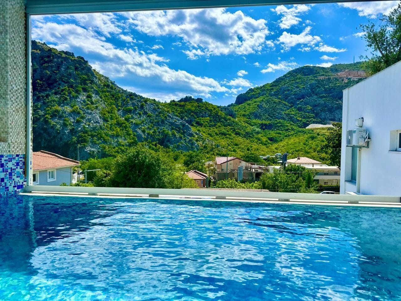 Una piscina con vista su un paesaggio montuoso e edifici sullo sfondo.